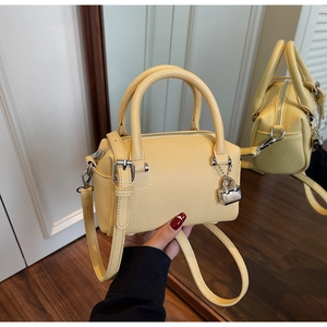 Detail of light yellow leather Boston bag featuring lychee grain and silver hardware buckle