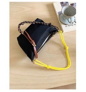 Detail of black nylon crescent bag with yellow braided rope handle and gold hardware