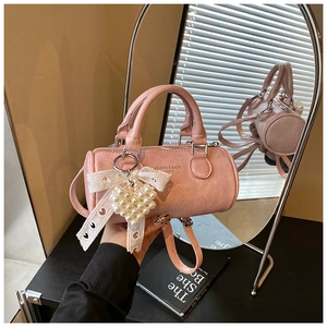 Detailed view of pink cylinder crossbody bag with lace bow and pearl heart charm