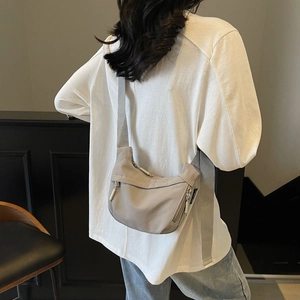 Detail of light grey nylon half-moon crossbody bag featuring side functional zipper pockets