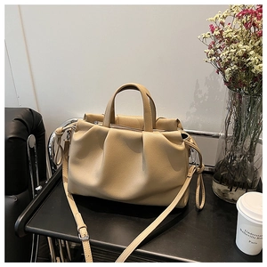 Detail der beige Falten-Beuteltasche mit weicher Ledertextur und abnehmbarem Gurt