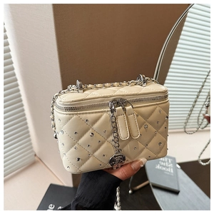 Detail of quilted beige box bag featuring sparkling rhinestones and silver rose pendant