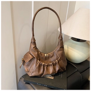 Detail view of brown vintage shoulder bag with pleated pocket and golden zippers