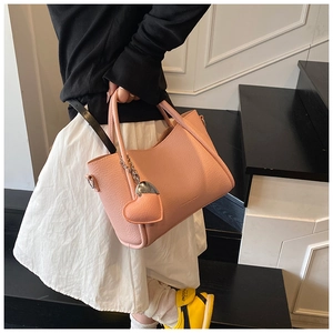 Detailed view of pink pebble leather handbag with heart charm and silver metal hardware