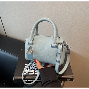 Close-up of light blue pebble leather mini Boston bag with silver lock and shoulder strap