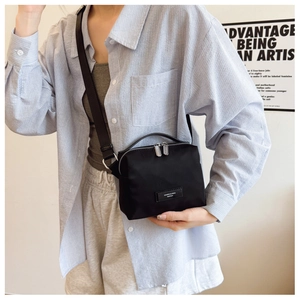 Détail du sac bandoulière en nylon noir avec double fermeture éclair et sangle