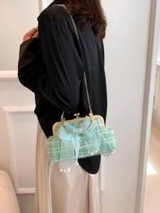 Light green tweed shell bag with blue bow and pearl charms worn by a model