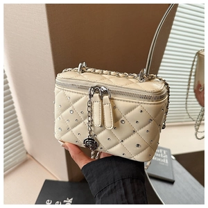 Detail of quilted beige box bag with rhinestone studs and rose-shaped silver zipper pull