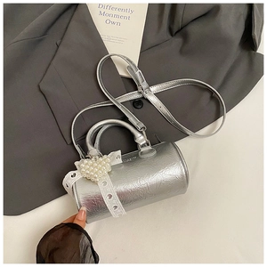 Detail of silver cylinder bag with pearl heart pendant and white lace trim on blazer