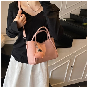 Pink lychee grain leather handbag with heart pendant and detachable shoulder strap detail