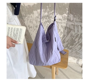 Dettaglio borsa tote in tela viola plissettata con tracolla regolabile in scena
