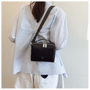 Vue arrière détaillée d'un petit sac bandoulière en nylon noir porté par un mannequin réel