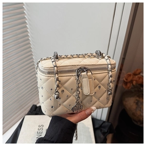 Close-up of cream quilted box bag with silver studs and floral zipper charm