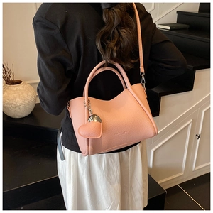 Detail of pink lychee pattern handbag with fashion embossing and heart leather charm