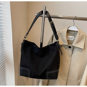 Detail of black tote bag showing leather reinforced corners and white contrast stitching