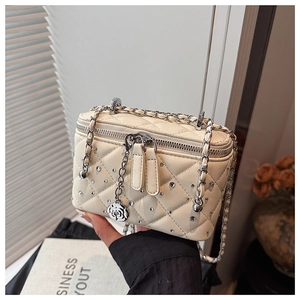 Detail of cream quilted vanity bag with crystal studs and rose metal charm