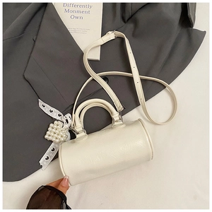 Macro shot of white cylinder handbag with glossy texture and pearl heart charm