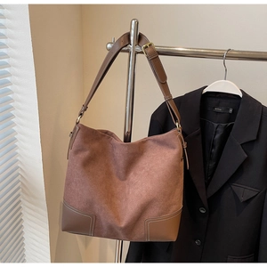 Detail of vintage brown suede tote bag featuring contrast leather patches and metal buckles