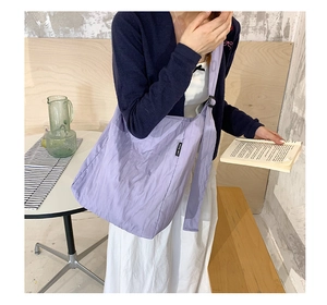 Vista dettagliata della borsa a tracolla trapuntata viola chiaro indossata da una modella
