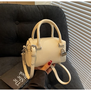 Detail of off-white lychee pattern Boston handbag with silver lock and shoulder strap