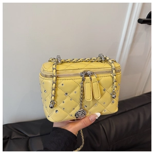 Close-up of yellow quilted rhinestone bag with silver chain and rose pendant detail