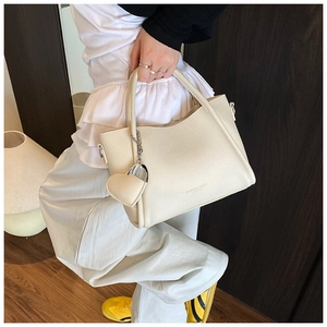 Detail of cream white pebbled leather handbag with heart pendant and fashion logo