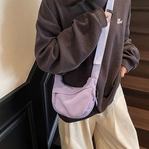 Close-up of a lavender crescent crossbody bag showing nylon texture and brand tag detail