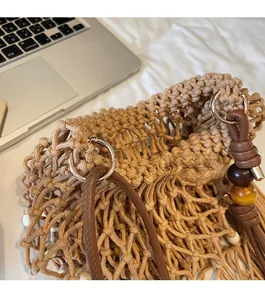 Close-up of woven shoulder bag with metal buckle and hanging wood bead detail
