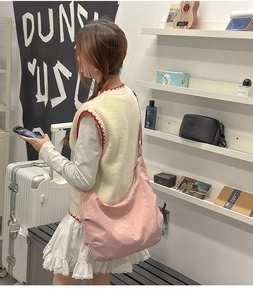 Detailed view of pink canvas dumpling bag worn crossbody with wide shoulder strap