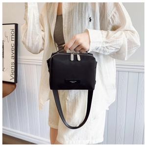 Détail du sac bandoulière en nylon noir avec poignée supérieure et écusson logo