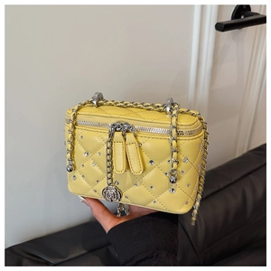 Detail of yellow quilted leather vanity bag with silver chains and rhinestone accents