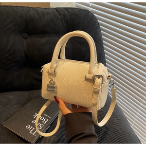 Detail of cream-colored pebble leather mini boston bag with silver lock and shoulder strap