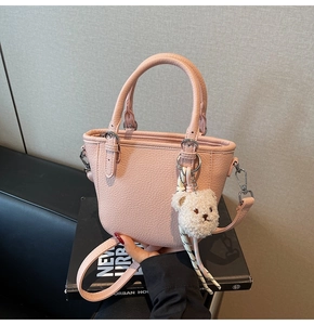 Close-up of pink lychee grain tote bag with silver hardware and cute teddy bear charm