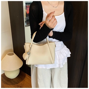 Detail of cream pebbled leather bucket bag with heart pendant and silver chain strap