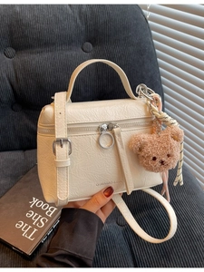 Creamy white pleated bucket bag with brown plush bear charm and twin ring zippers