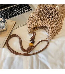 Detail of bohemian hollow woven bag with brown beaded strap and long decorative tassels