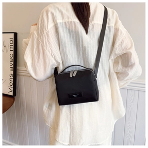 Détail d'un petit sac bandoulière noir en tissu avec double fermeture et poignée top