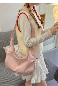 Side view of pink nylon crescent bag with heart embroidery on a female model