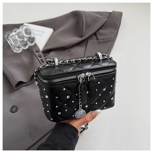 Close-up of black quilted box bag with silver studs and camellia flower charm detail
