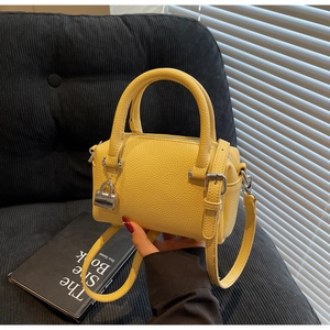 Detail of bright yellow boston handbag with lychee pattern leather and silver pendant