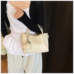 Close-up of off-white lychee pattern leather bucket bag with heart charm detail