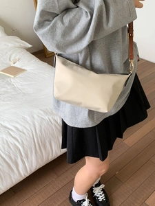 Minimalist beige crossbody bag with adjustable brown strap and gold metal hardware