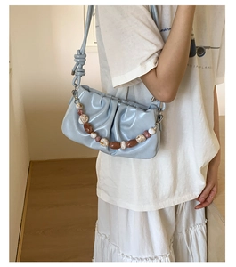 Detail of light blue pleated cloud bag featuring marble texture decorative beads
