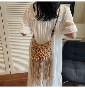 Detail of hand-woven hollow bag with wooden beads and long tassels in boho style
