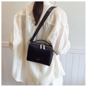 Vue arrière d'un sac bandoulière noir porté sur une chemise à rayures