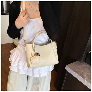 Close-up of a cream textured leather bucket bag with top handles and a heart charm