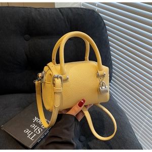 Detail of yellow pebbled leather mini Boston bag with silver padlock and top handles