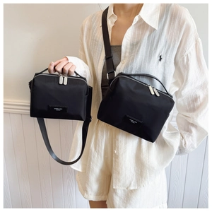 Détail de deux tailles de sacs à bandoulière en nylon noir avec doubles zips argentés