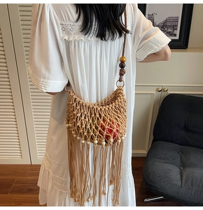 Detail of woven beach bag featuring bohemian fringe and decorative wooden beads