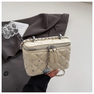 Close-up of beige quilted vanity bag with crystal studs and rose flower zipper charm
